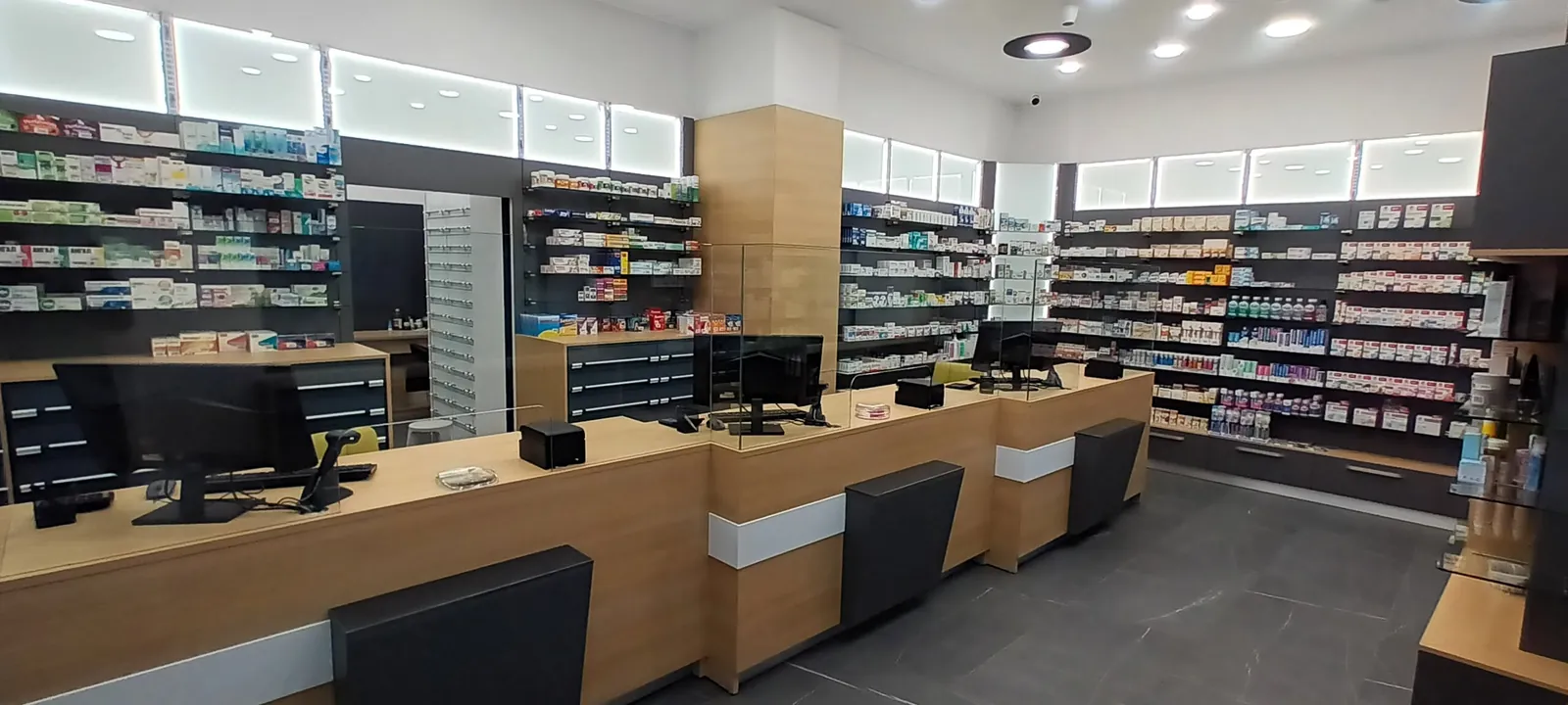 Аптека със стелажи AXON C в търговската зала и касова зона с чекмеджета под плотовете